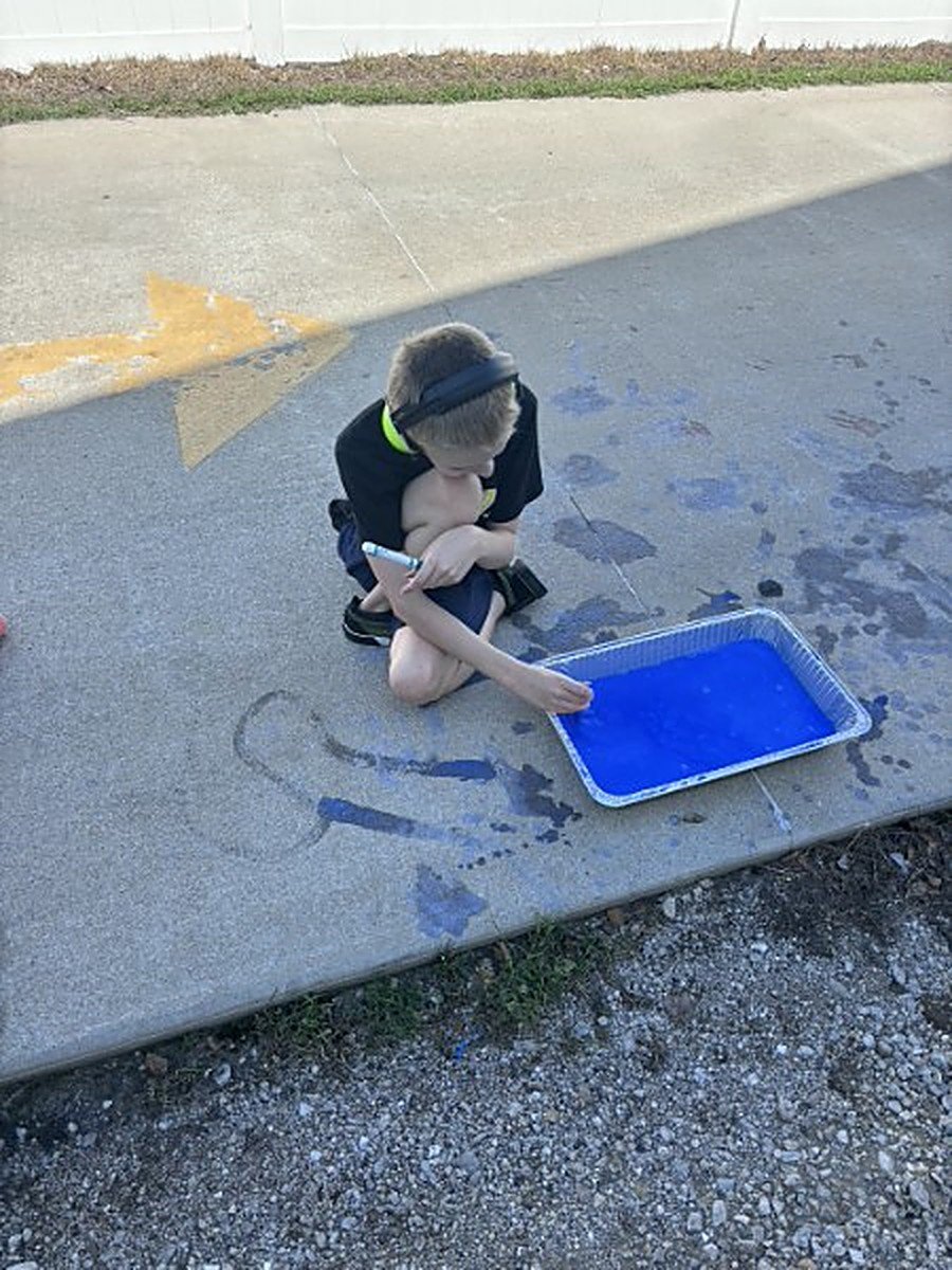 A participant working with blue colored water on the pavement